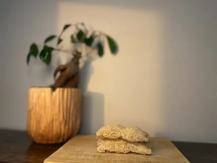 A stack of luffa scrub pads beside a wooden planter